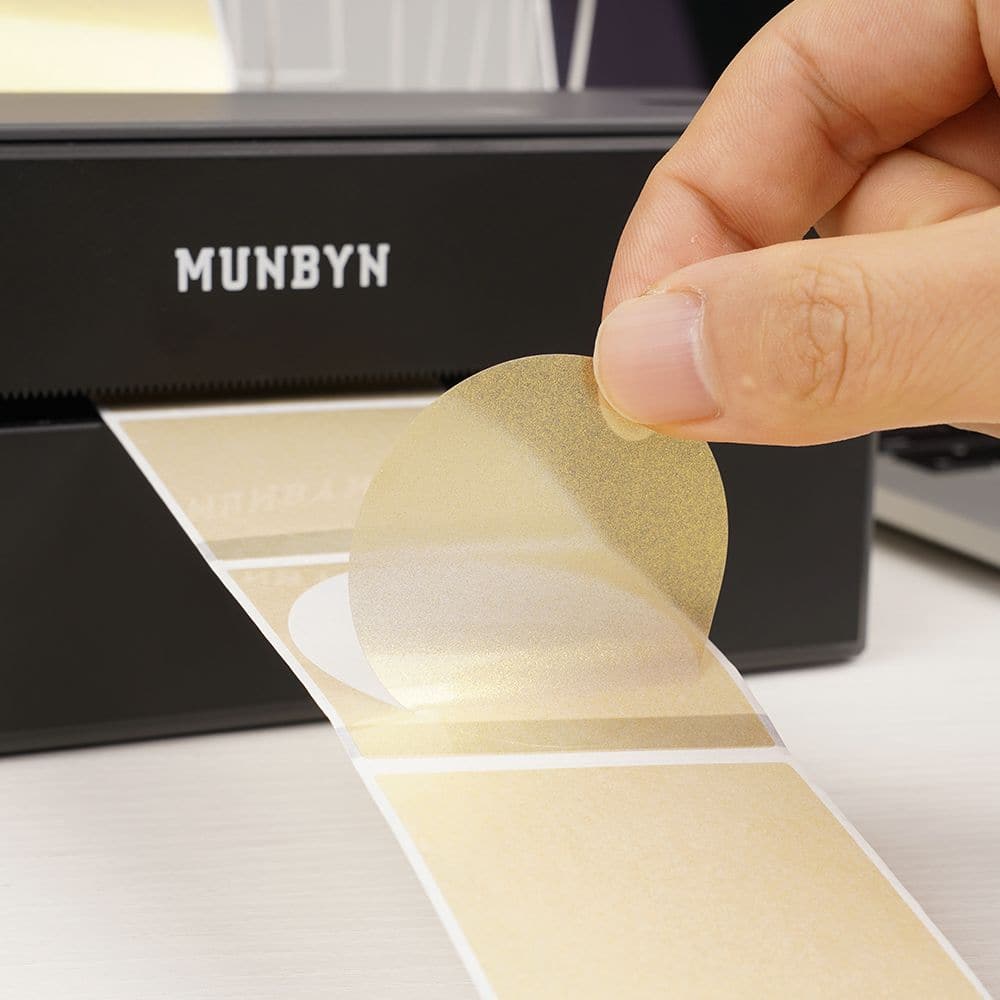 Close-up of 2-inch gold labels printed on MUNBYN label printer paper, showing shiny gold finish and adhesive backing.